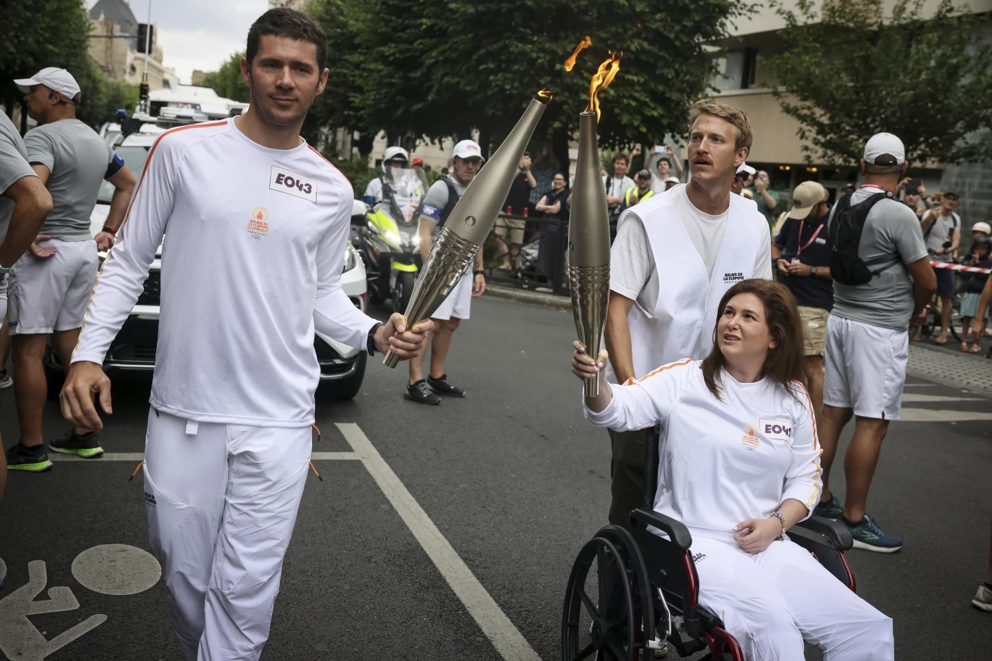 Nữ nhà báo Christina Assi (ngồi xe lăn) cầm đuốc Olympic cùng với Nicolas Fayeur (trái) tại Paris, Pháp vào ngày 21 tháng 7 năm 2024. Ảnh: AP